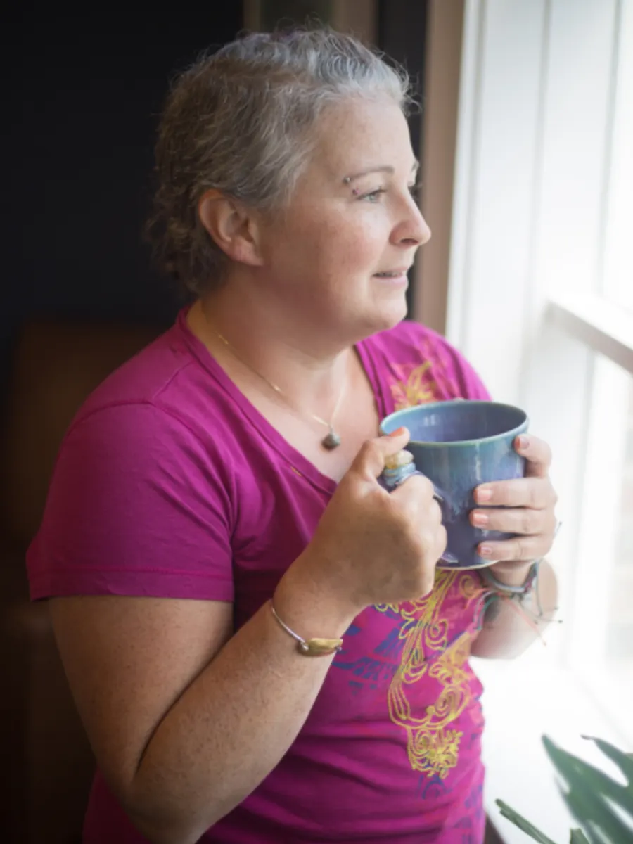 Woman enjoying a warm drink by a sunny window