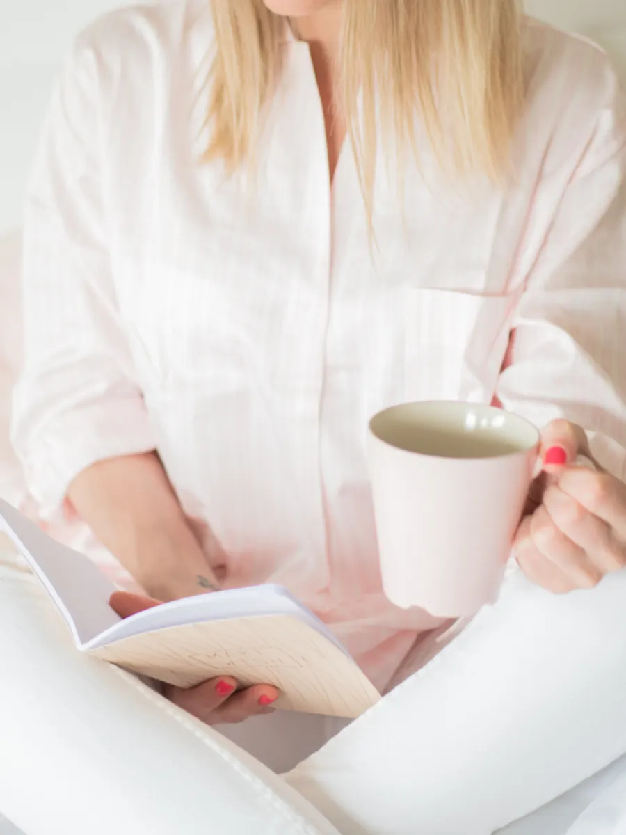 Woman relaxing in bed with tea and a book